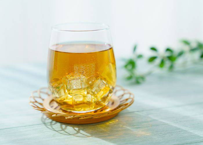 A chilled glass of mugicha on a flower-shaped coaster.